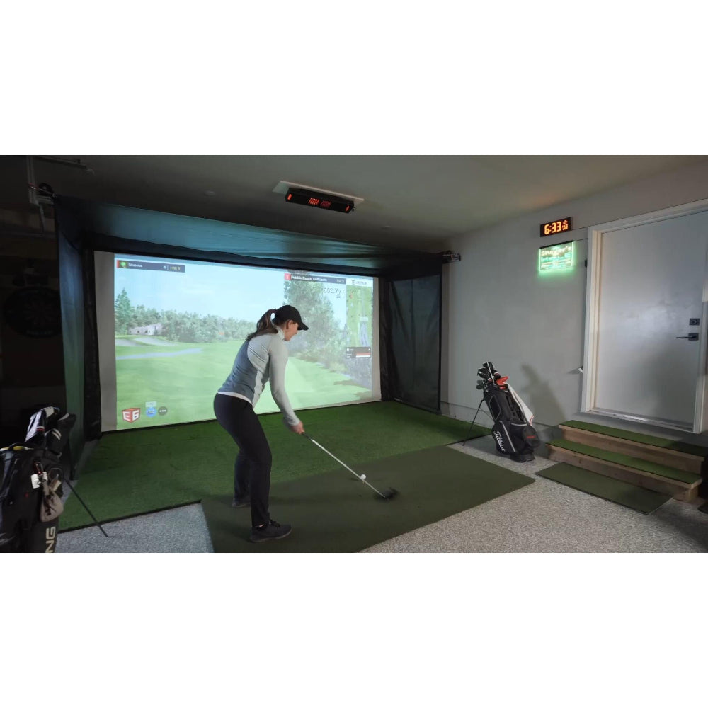 Indoor golf practice setup with a person swinging a golf club, Enclosure includes screens and a large projection of a golf course on the wall.